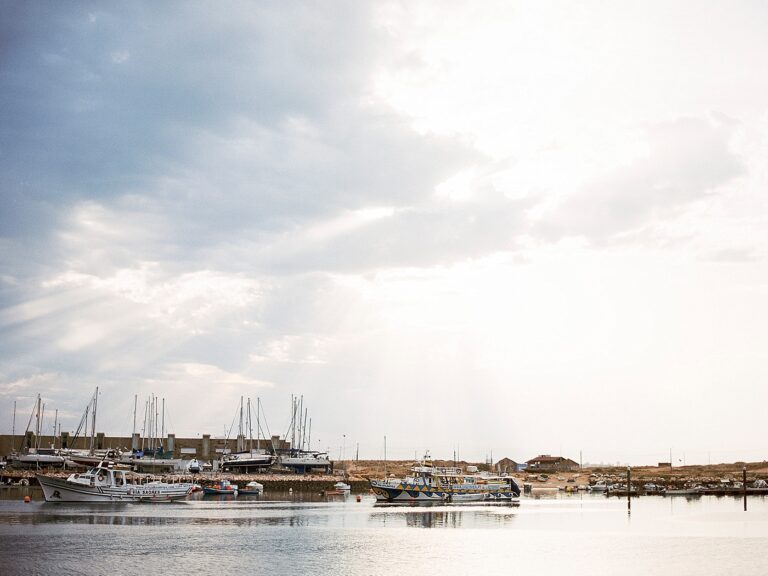 A view of boats on the water. In the background is a brown landscape.