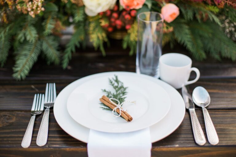A table setting with a sprig of greenery and stick of cinnamon.