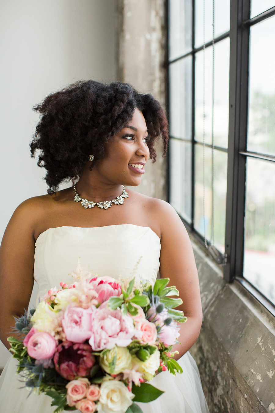 Gorgeous African American bride, wedding hairstyle and a colorful floral bouquet