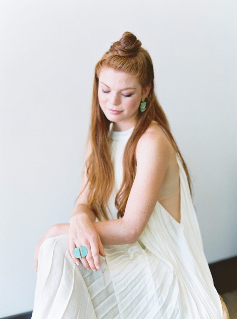 A woman in a breezy, white dress glances down