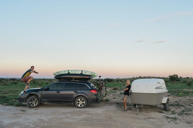 A man is pictured mid-jump in front of an SVU while a woman leans against a car trailer