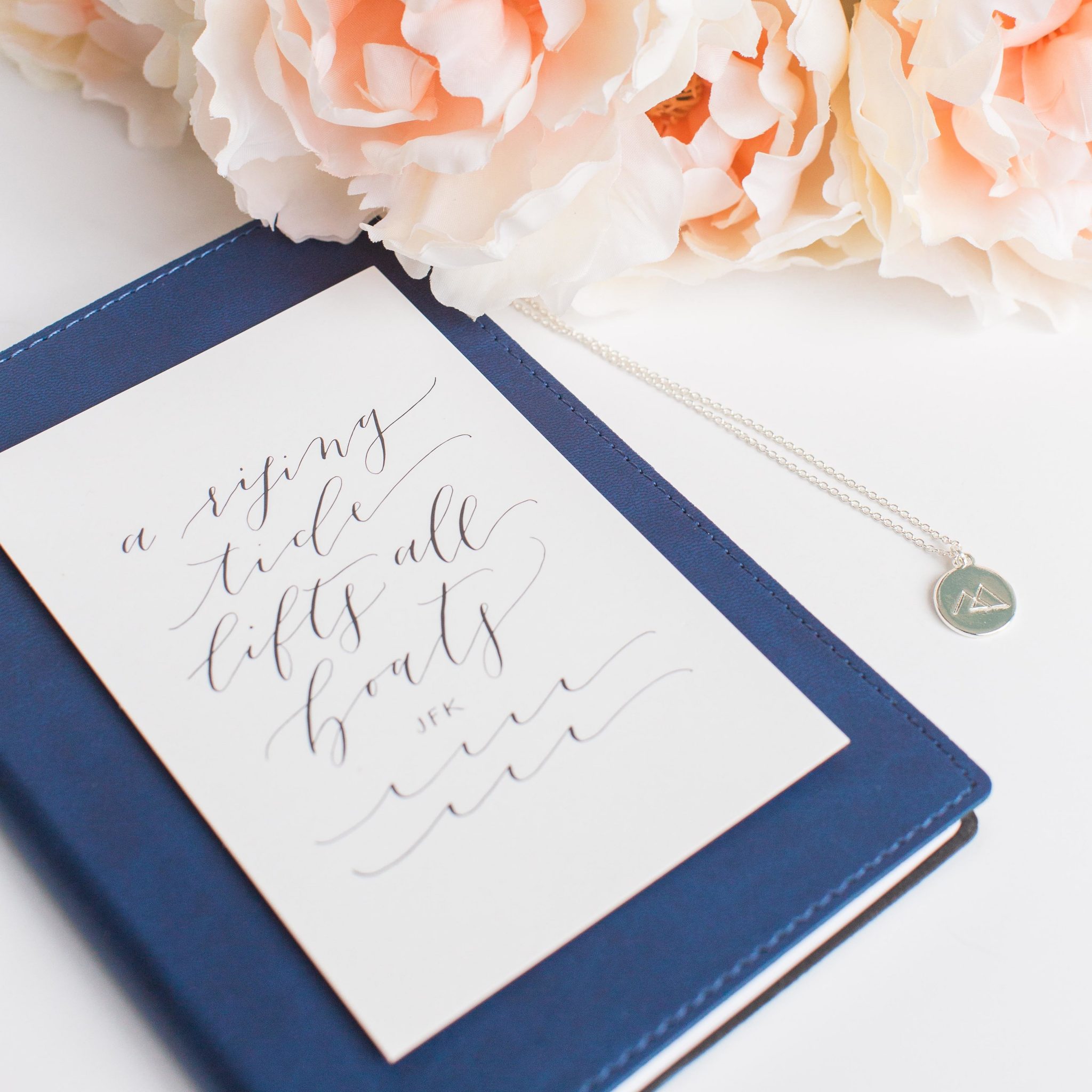 A Rising Tide Lifts All Boats quote on a notebook for the Rising Tide Society & HoneyBook Blog