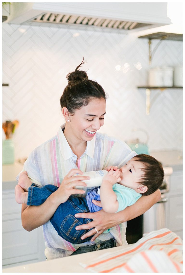 Young business owner feeding her baby a bottle.