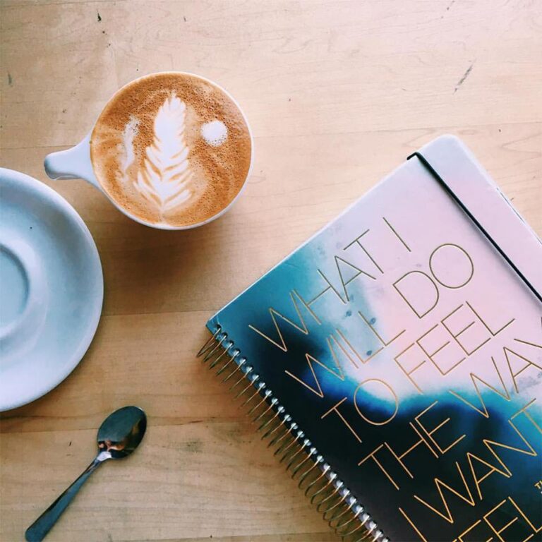 Flat lay of coffee and planner with an inspirational quote on the cover