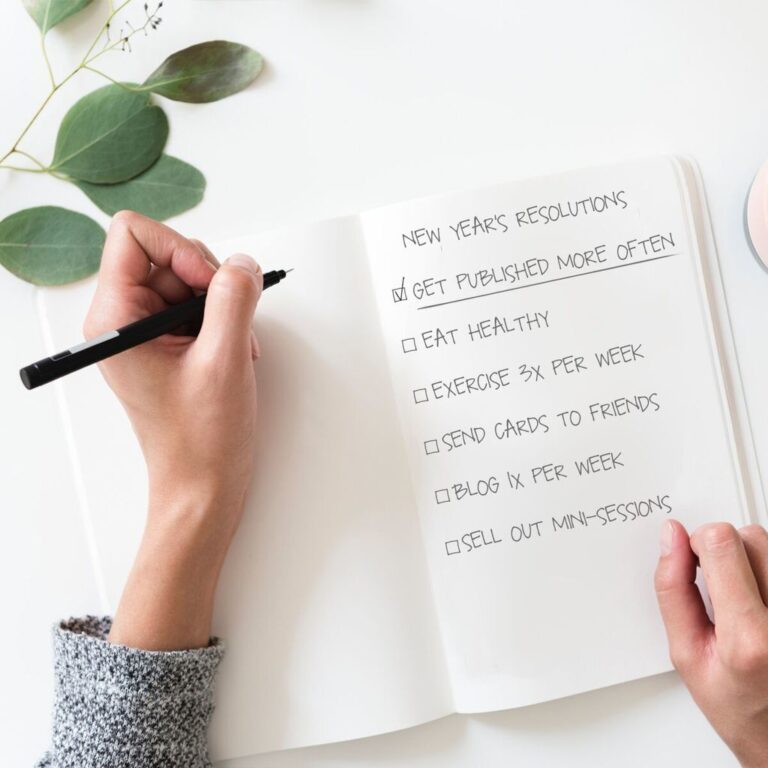 A hand writes a list of New Years Resolutions