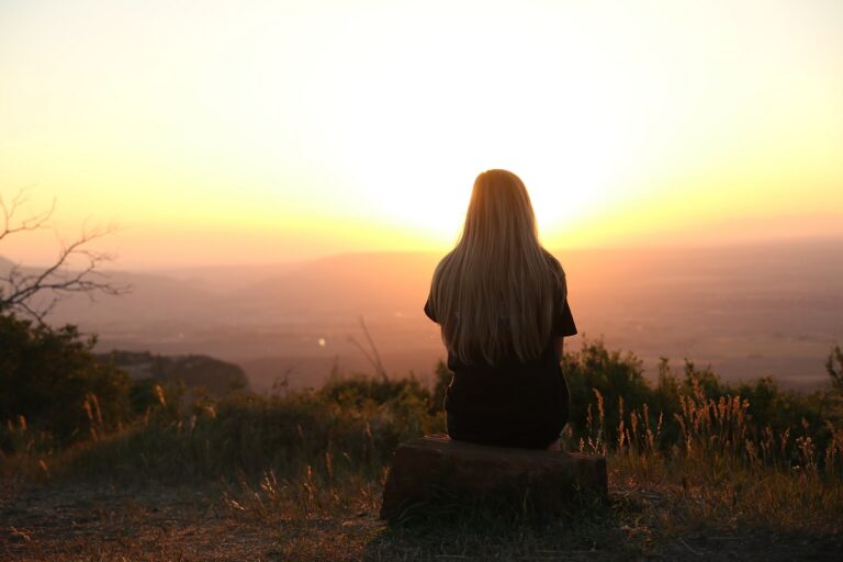 a girl watching the sunset over the mountains