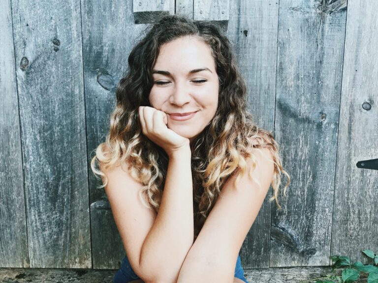Ambar Januel smiling with eyes closed and head resting in hands.