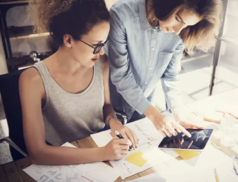 two women looking at a tablet learning about brand strategy