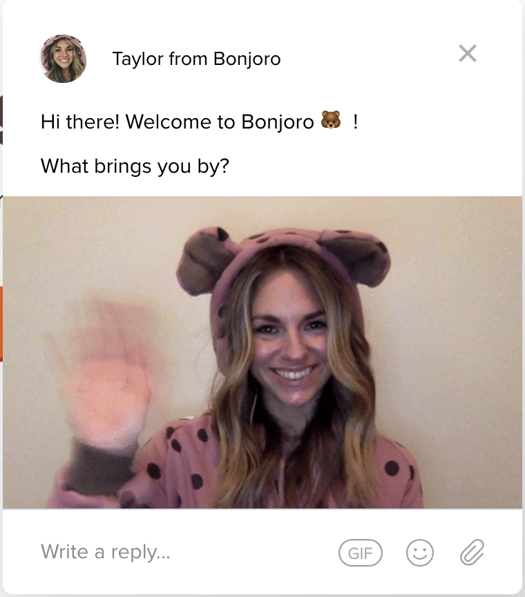 Inside an instant message window, a woman wears a polka-dotted jumper with a bear hoodie, waving at the camera