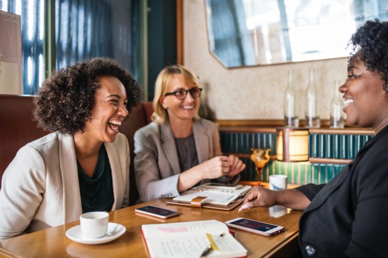 women laughing and working at a cafe table