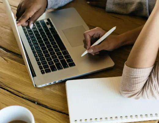 working on a laptop and notebook to create a virtual summit