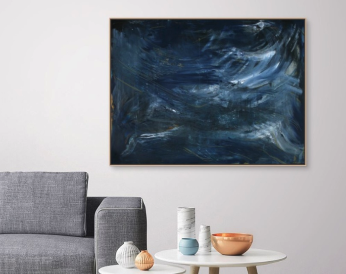 a living room scene with a grey couch, an accent table and a large painting