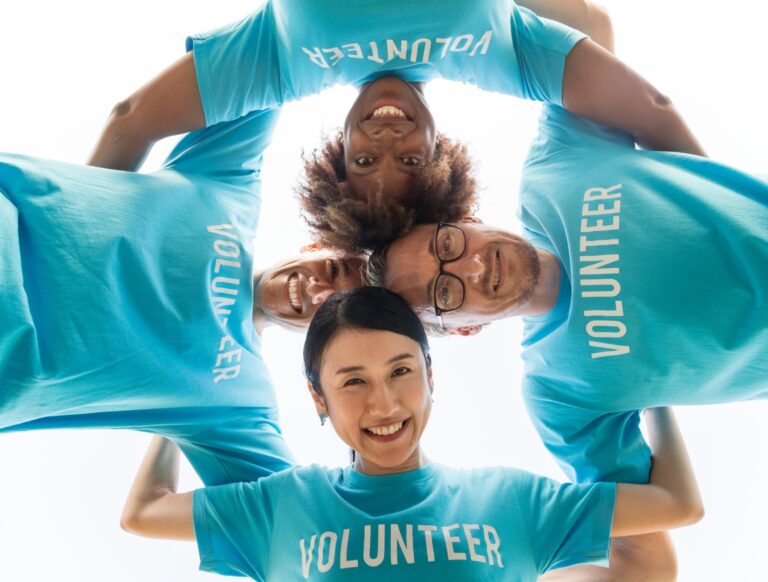 4 volunteers in teal shirts in a huddle