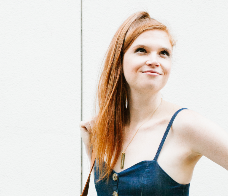 Close up of a woman standing in front of a white wall.