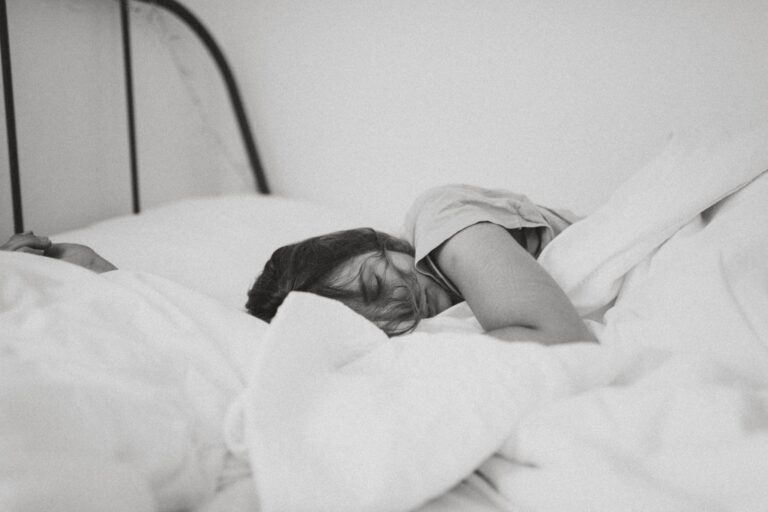 exhausted person laying in bed, not prioritizing their health