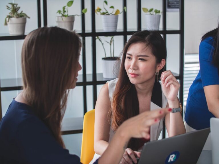 two women sitting at a desk with a laptop talking about small business goal setting