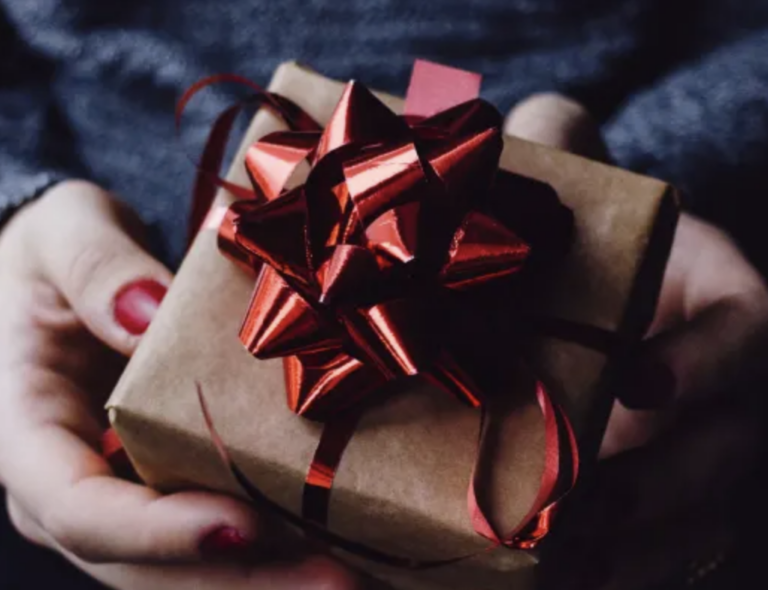 a woman's hands holding a branded gift for a client in a brown box with a red bow