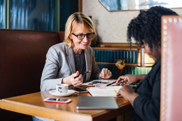 Woman in a business suite works on paper work with a client.