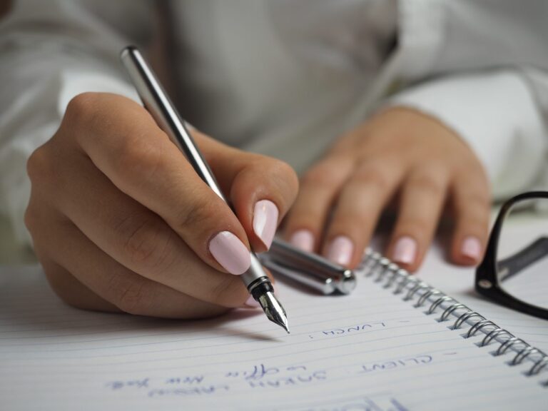a woman holding a pen writing in a notebook