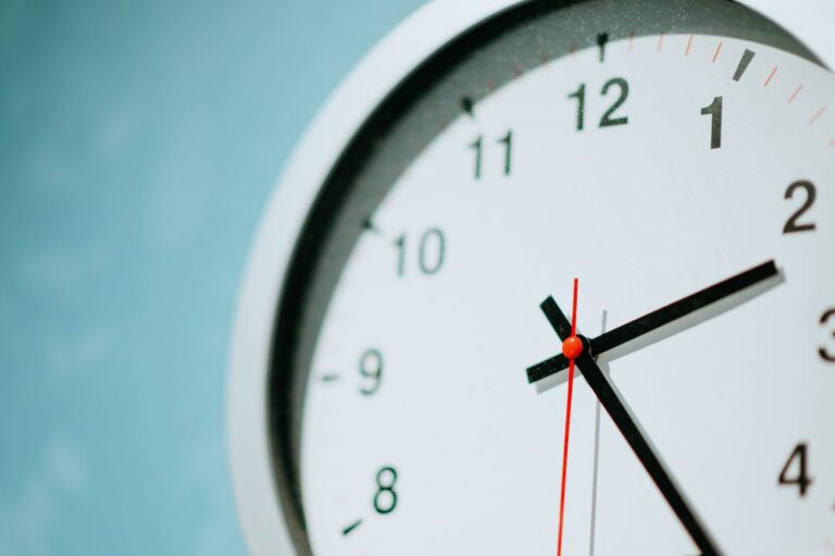 Close up of a white clock on a teal wall.