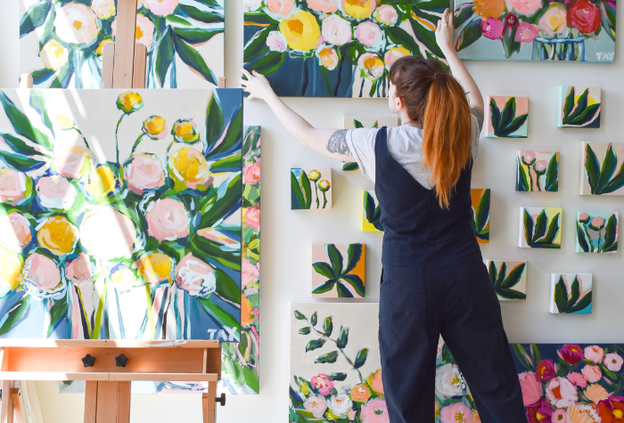 an artist hanging paintings on a wall