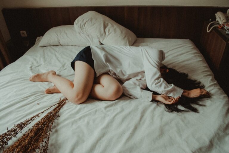 woman laying on a bed with dried flowers