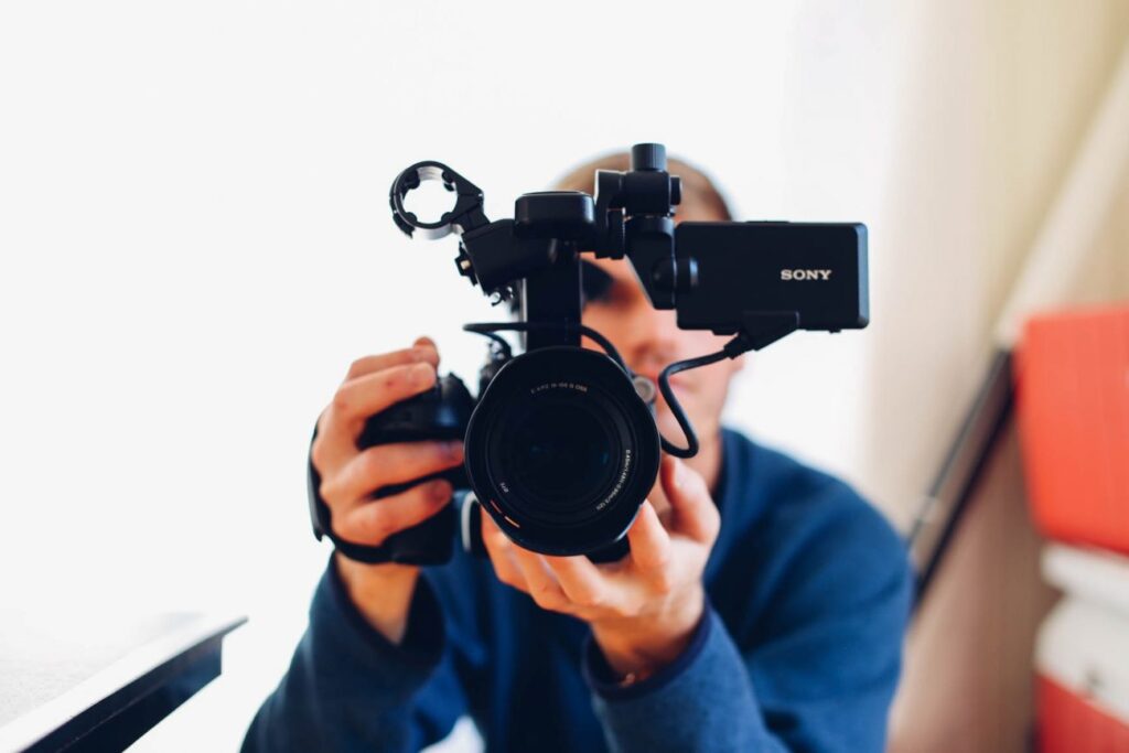 Man looking through video camera lens.