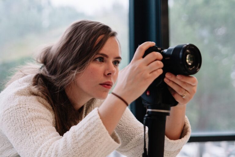 A woman adjusts a DSLR camera on a stand