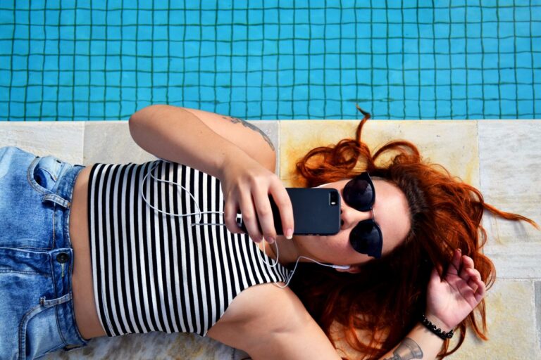 woman sitting on phone by the pool