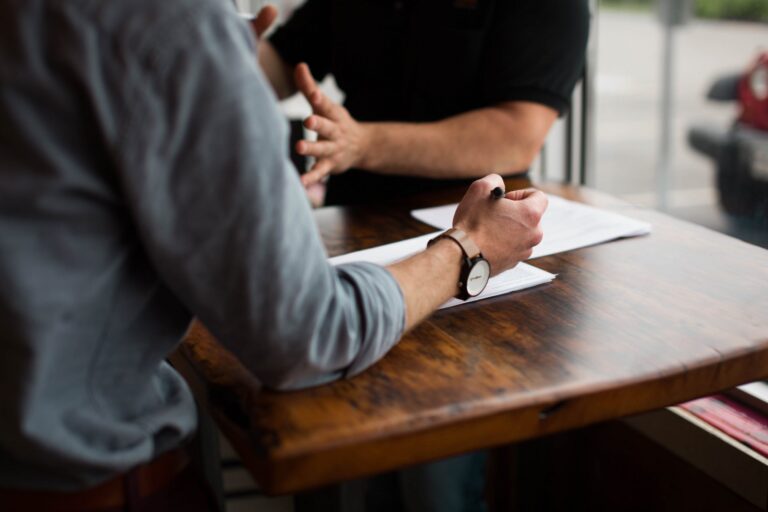 Close up of two men working at a wooden desk