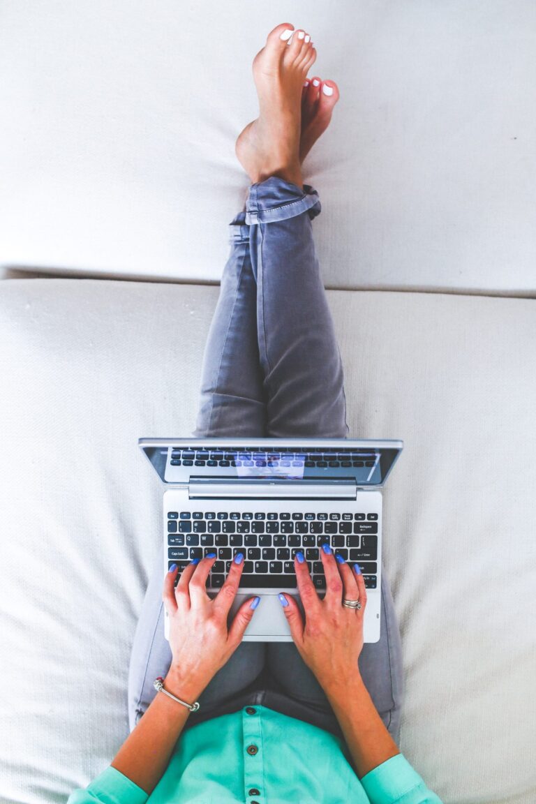 An aerial view of a woman lounging on a soft surface, working on a laptop