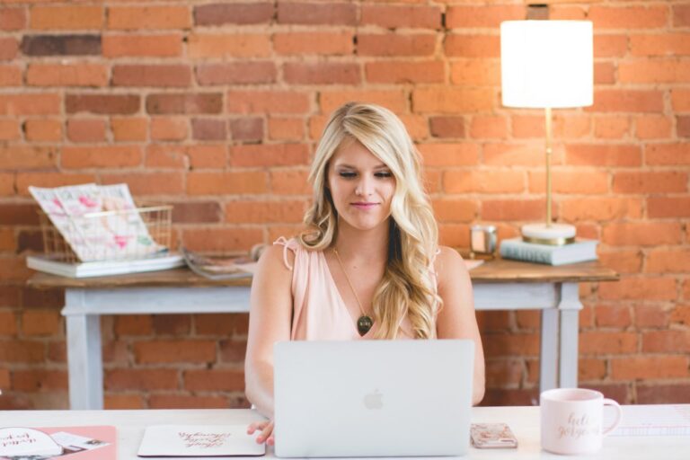 Woman with blonde hair works at laptop.
