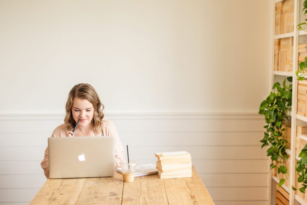 woman on a laptop with a stack of papers