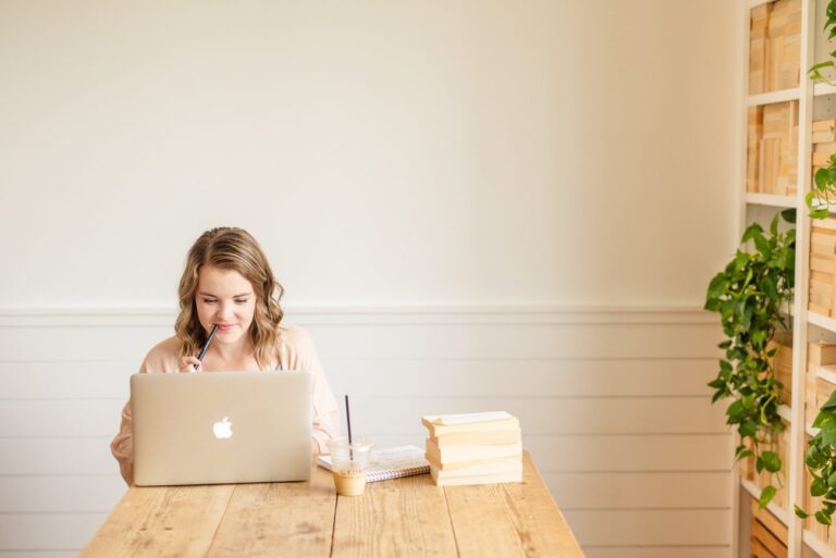 woman on a laptop with a stack of papers