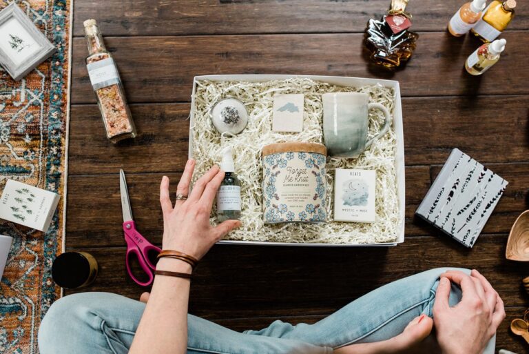 a person sitting cross legged on the floor in front of a gift box with various gifts inside