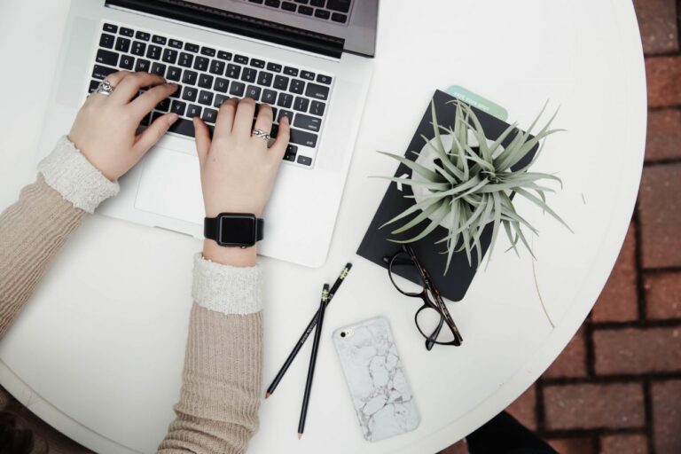 typing on a laptop with a plant