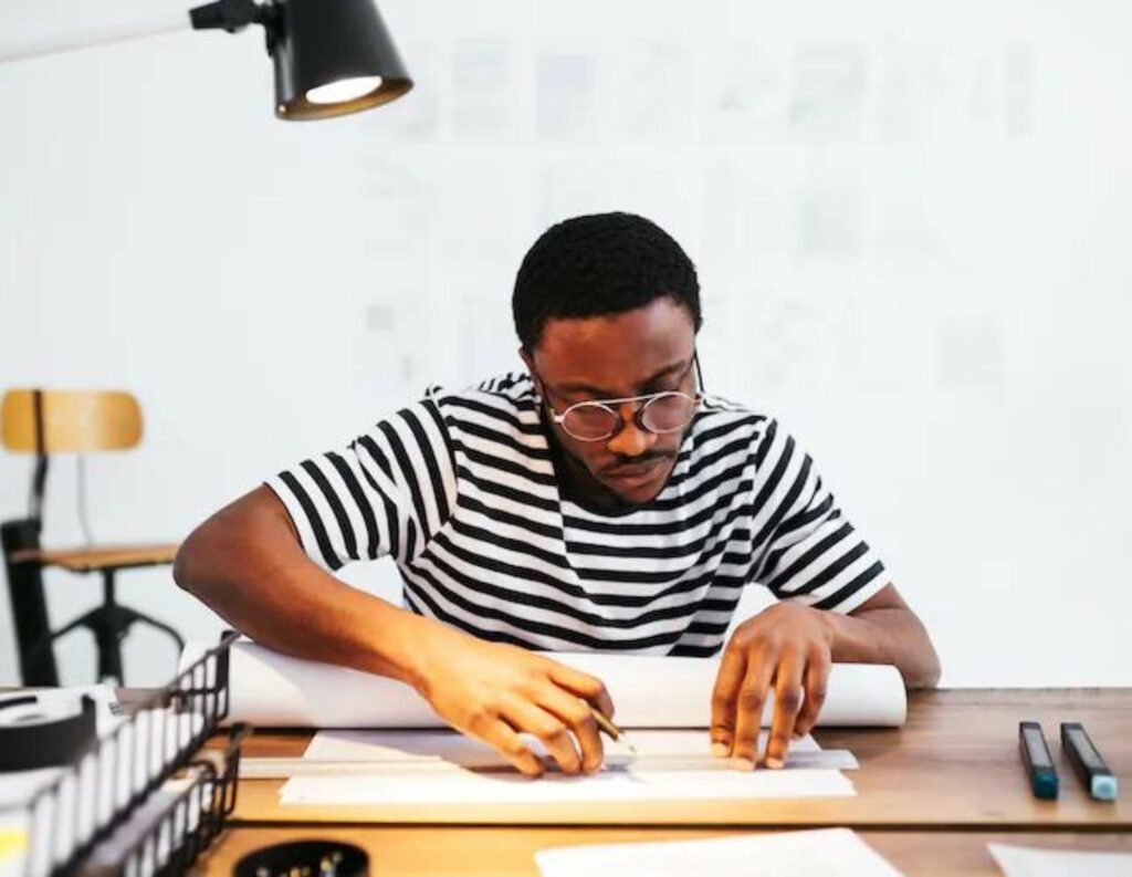 Man sits at desks and drafts a plan.