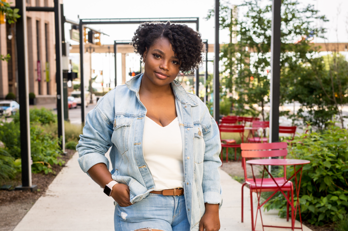 Woman wearing a jean jacket with one hand on hip.