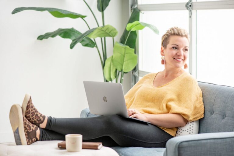 Woman with feet up using a laptop and smiling.