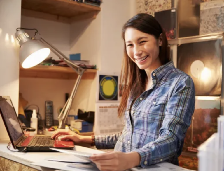 a woman at a desk smiling and learning how to control her business expenses