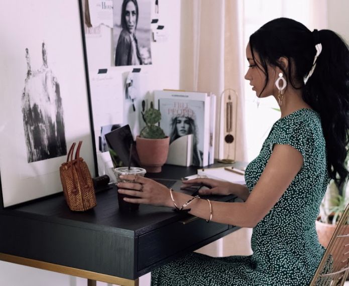 Woman sitting at a desk with an iced coffee.