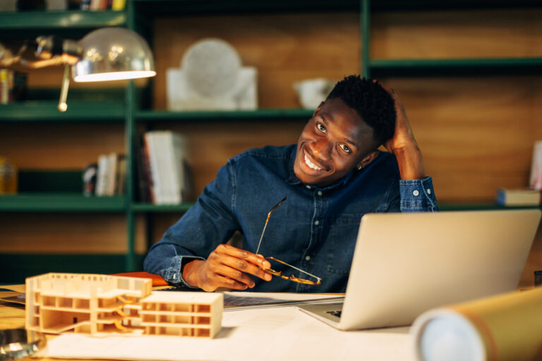 Young Architect smiles while at desk.