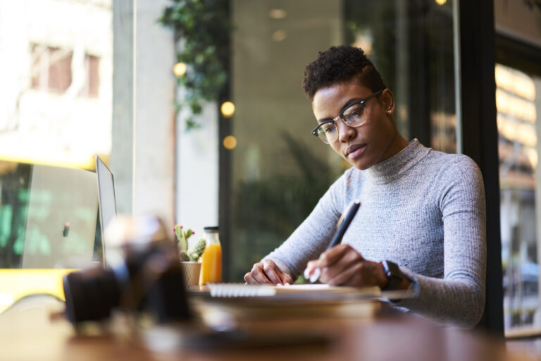 A woman in glasses works at a table