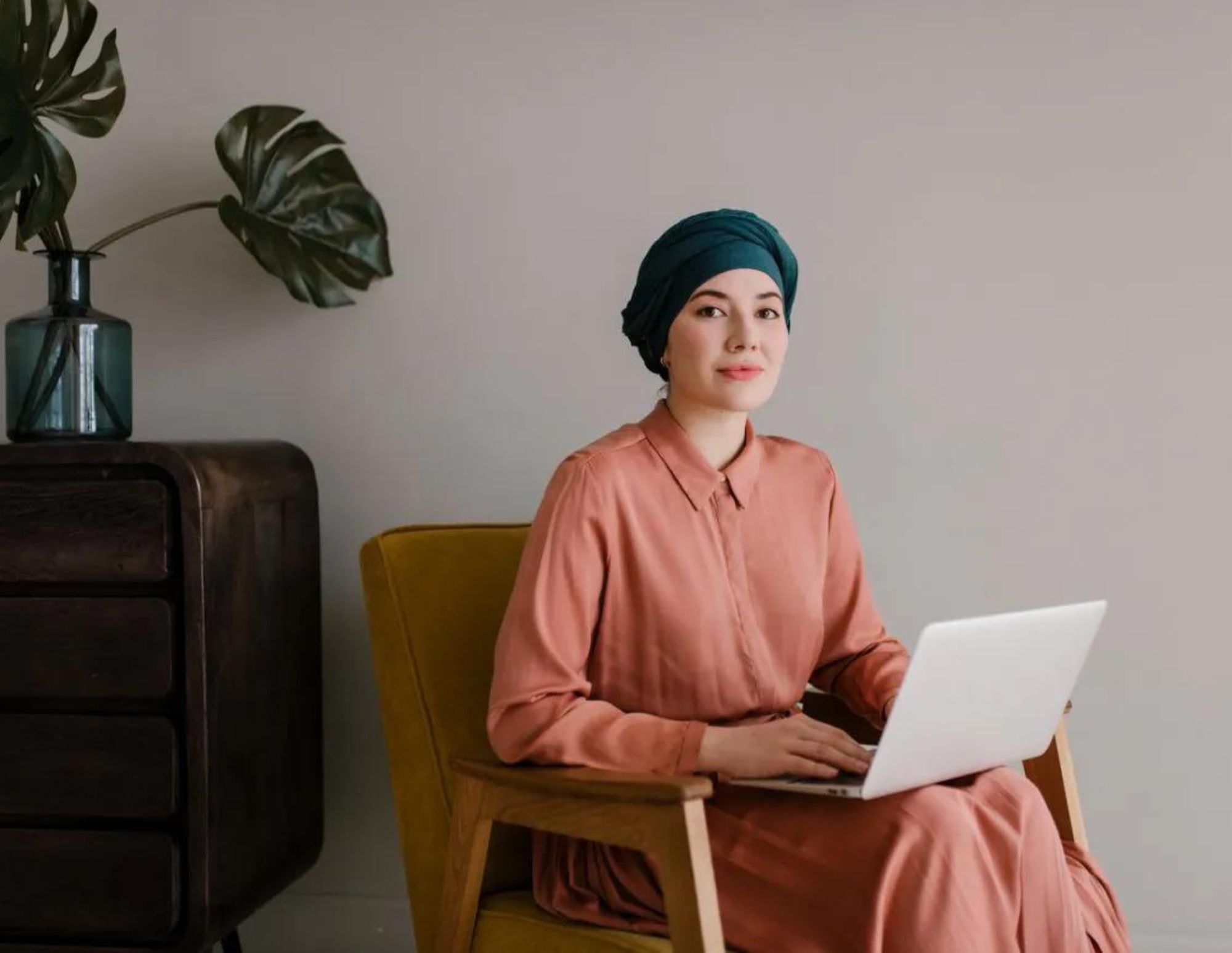 Woman sits with laptop in chair.