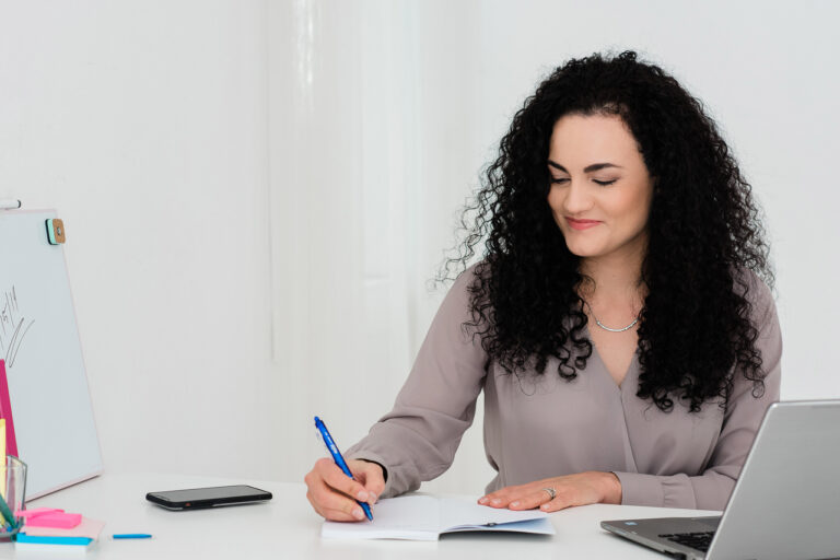 Woman working on client strategy as her desk, writing on a pad with a pen