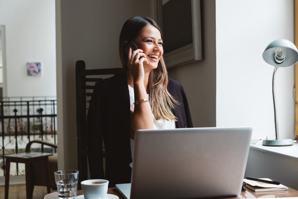 Businesswoman Talks On A Phone While Working On Laptop
