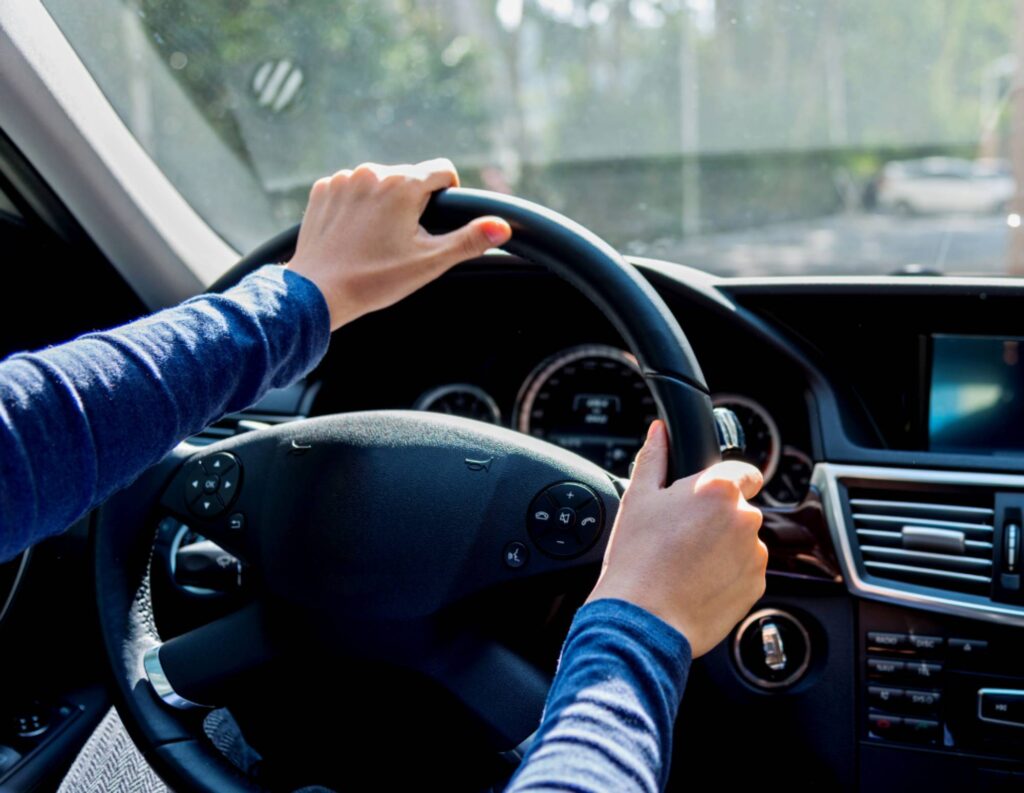 Person driving with hands on the steering wheel