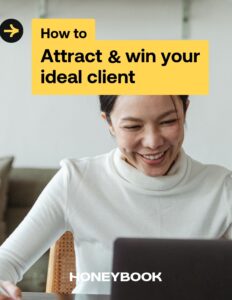 Woman looks at screen and smiles wearing a white turtleneck on the cover of the attract and win your ideal client guide.