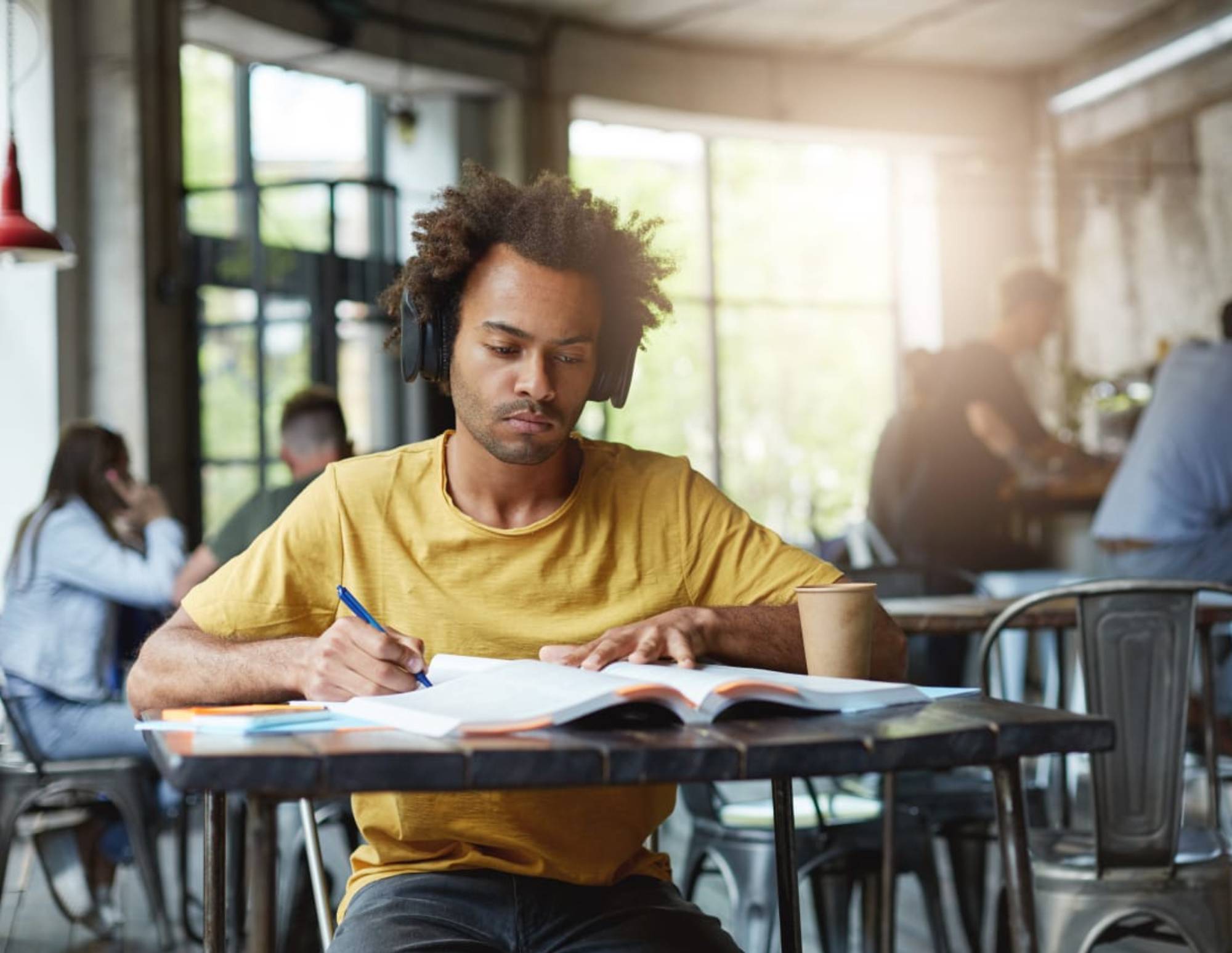 Man at a cafe writing in a book and working on his brand story