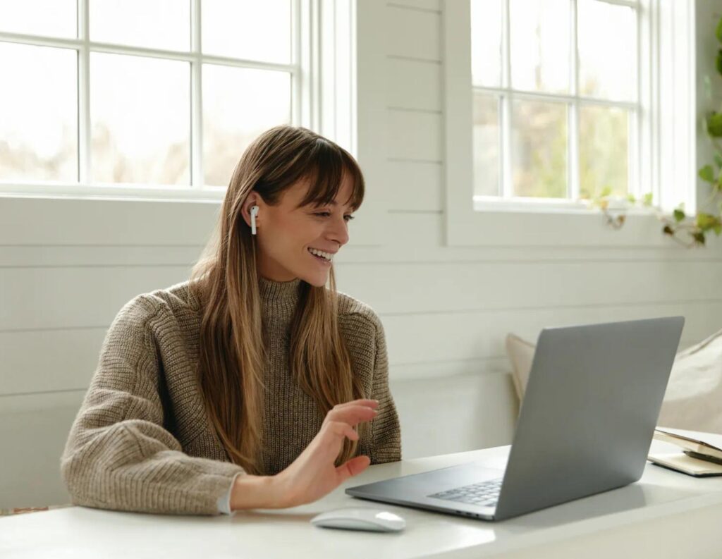 Woman with earbuds smiles at laptop while creating a lead gen quiz.
